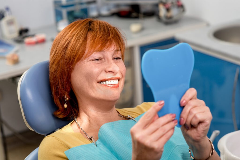 Woman looking into mirror at new dentures
